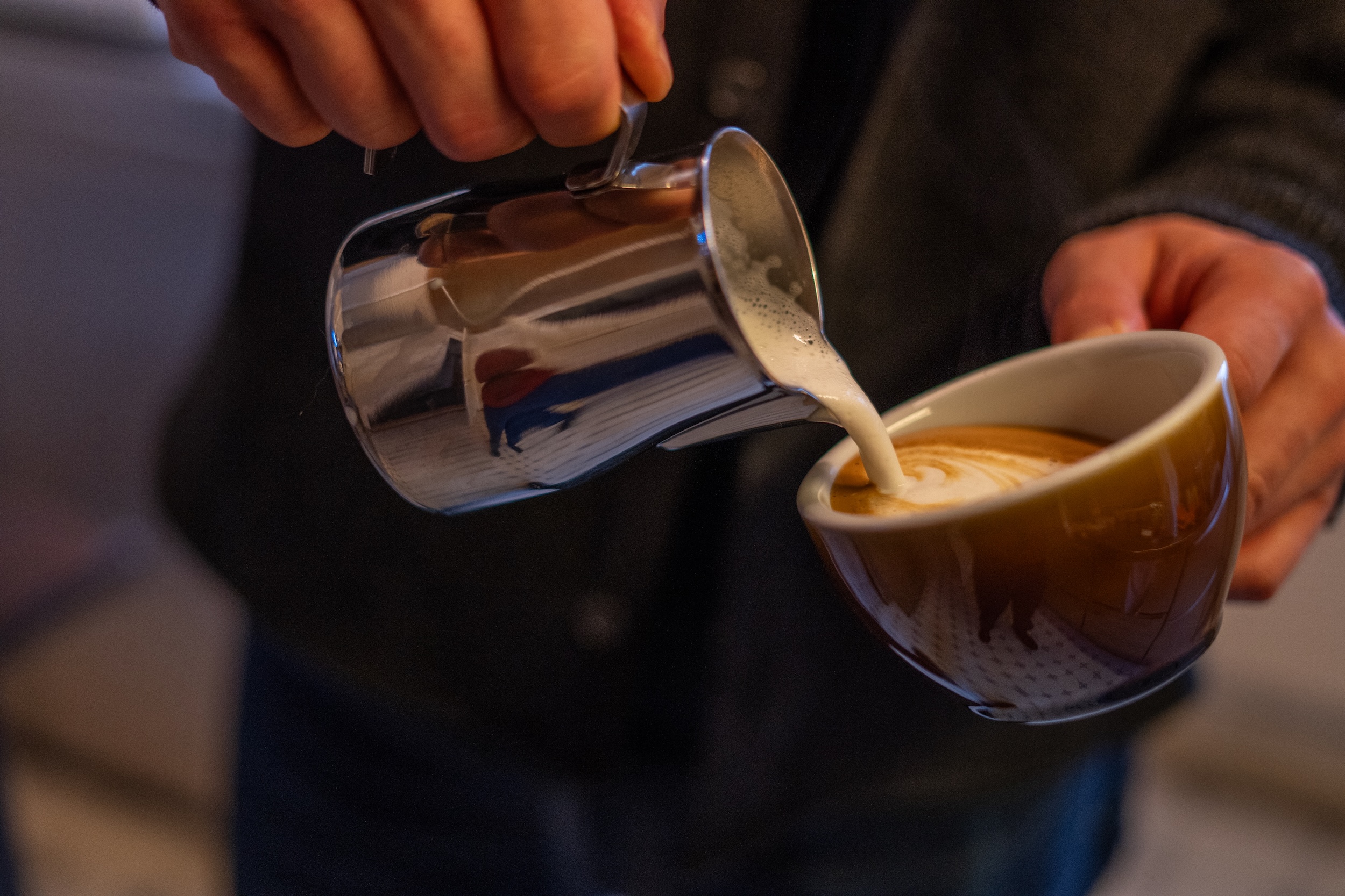 Jemand giesst Milch in eine Tasse