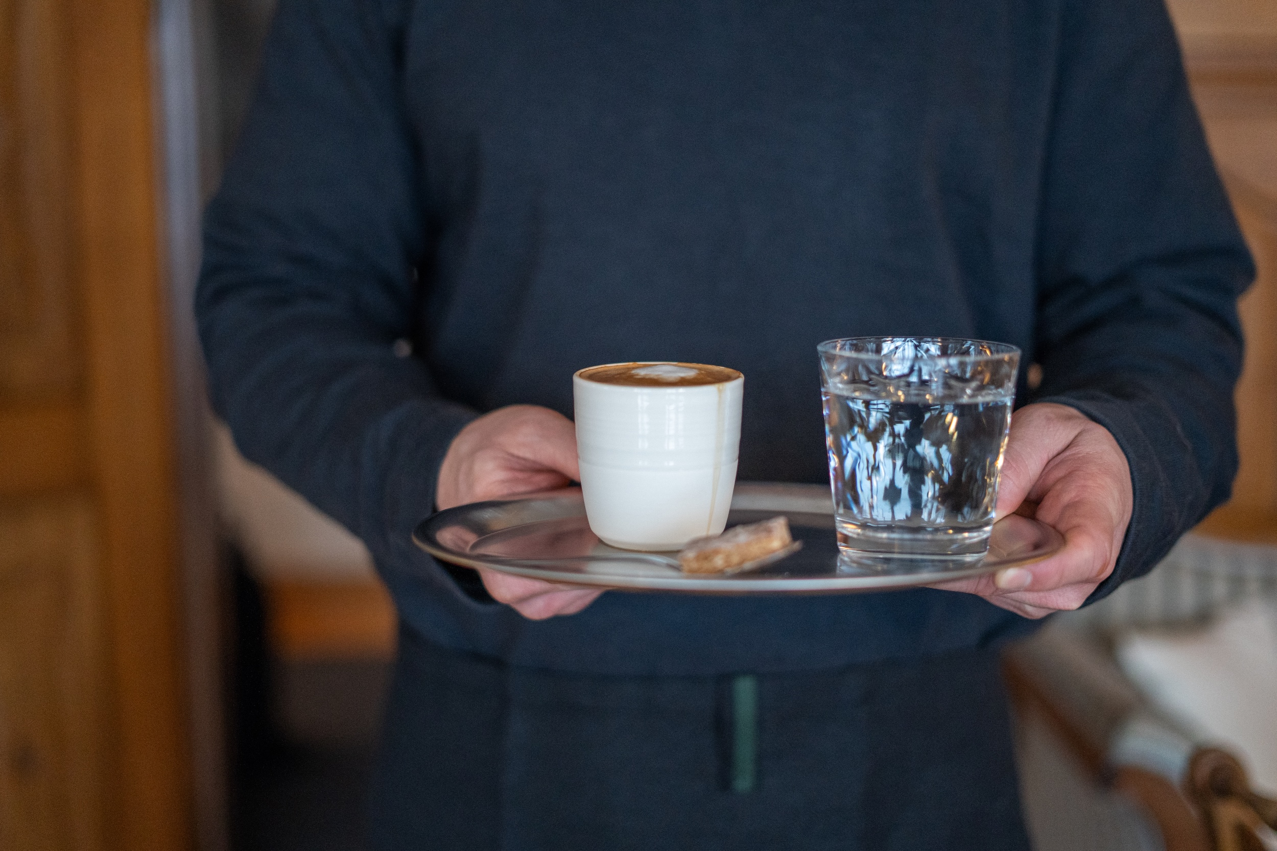 Jemand serviert einen Kaffee im Kafi Blumi